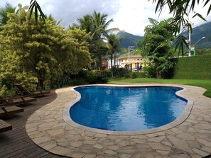 Una piscina al aire libre, sillones reclinables de piscina