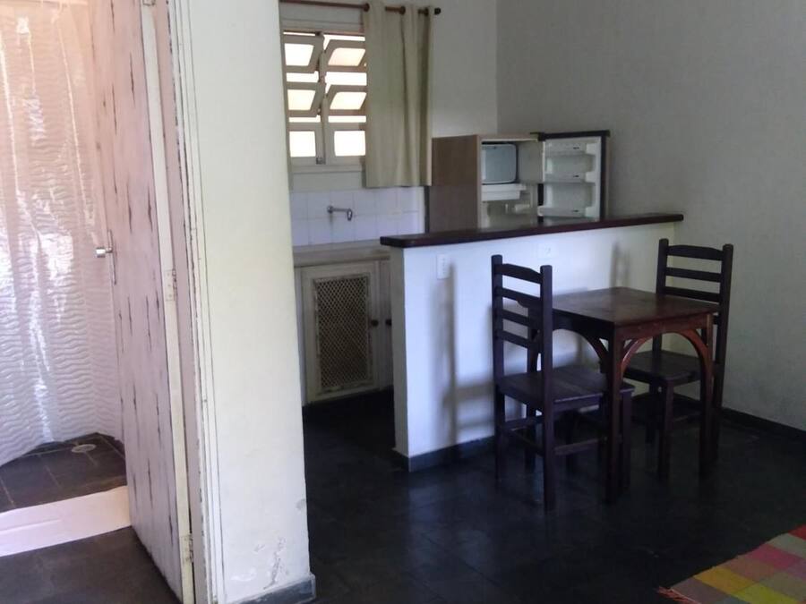 Una cocina compacta con comedor, un refrigerador pequeño y una lámpara colgante.