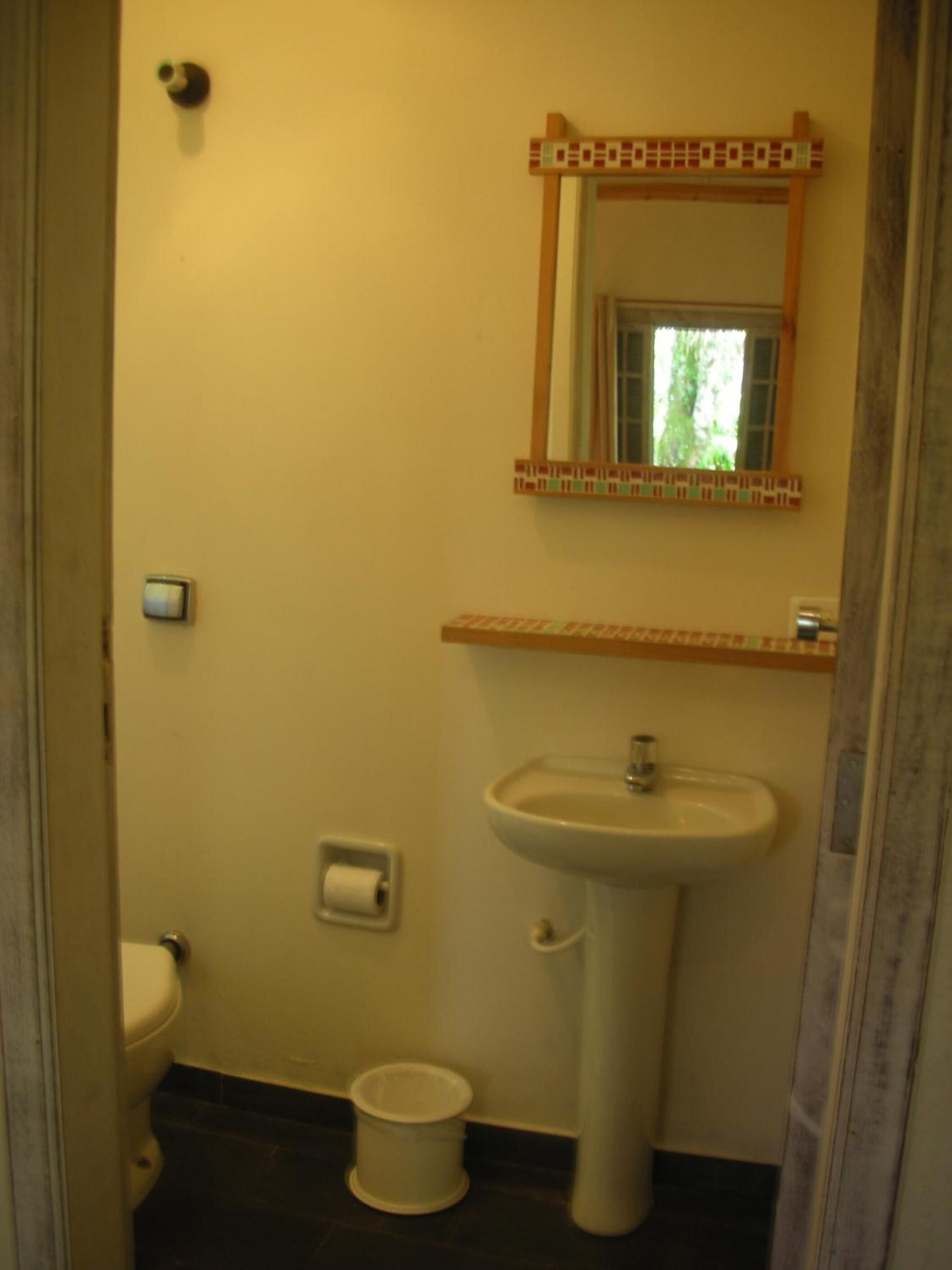 Un baño pequeño con inodoro, lavamanos y espejo.