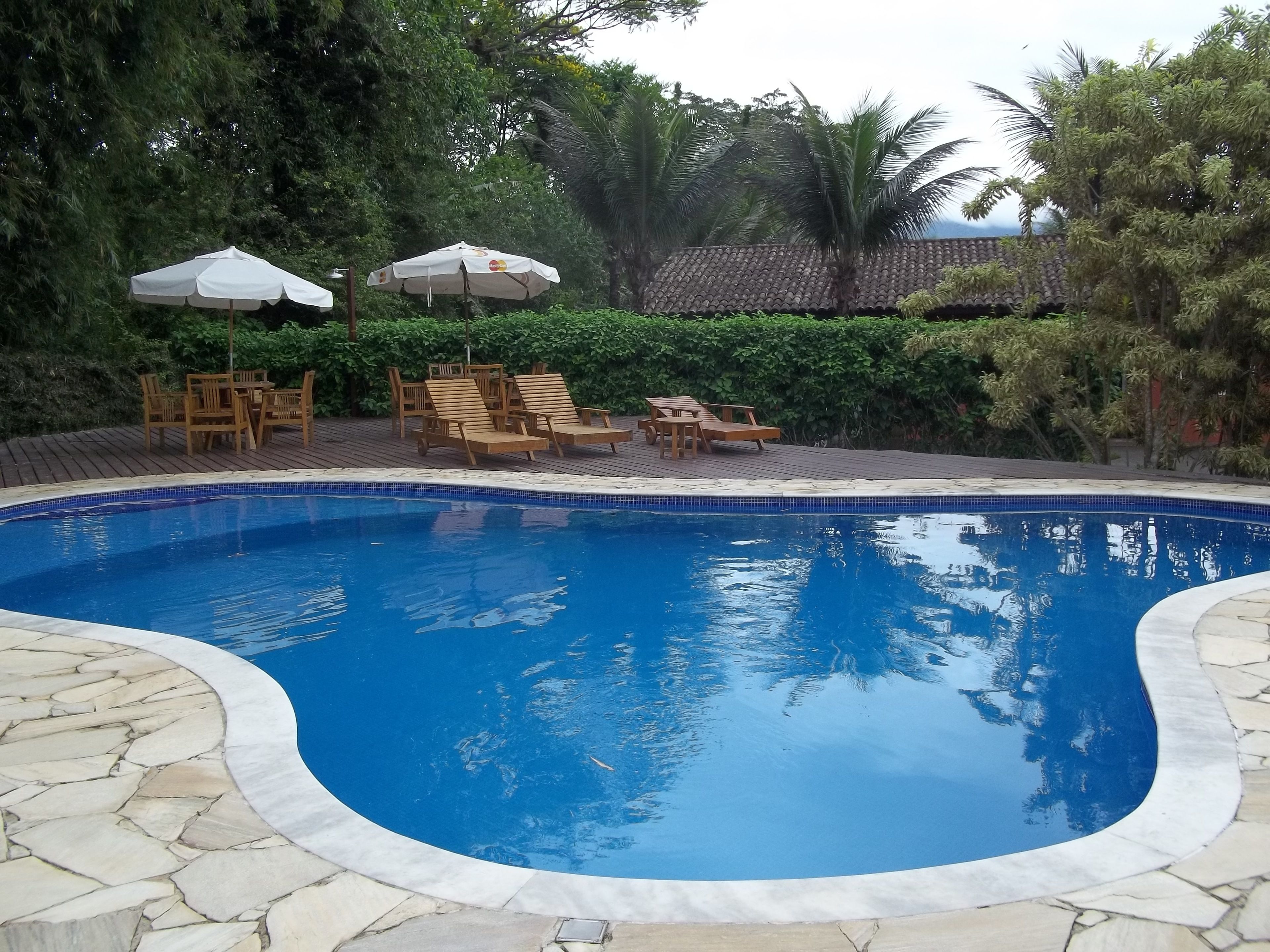 Una piscina al aire libre, sillones reclinables de piscina