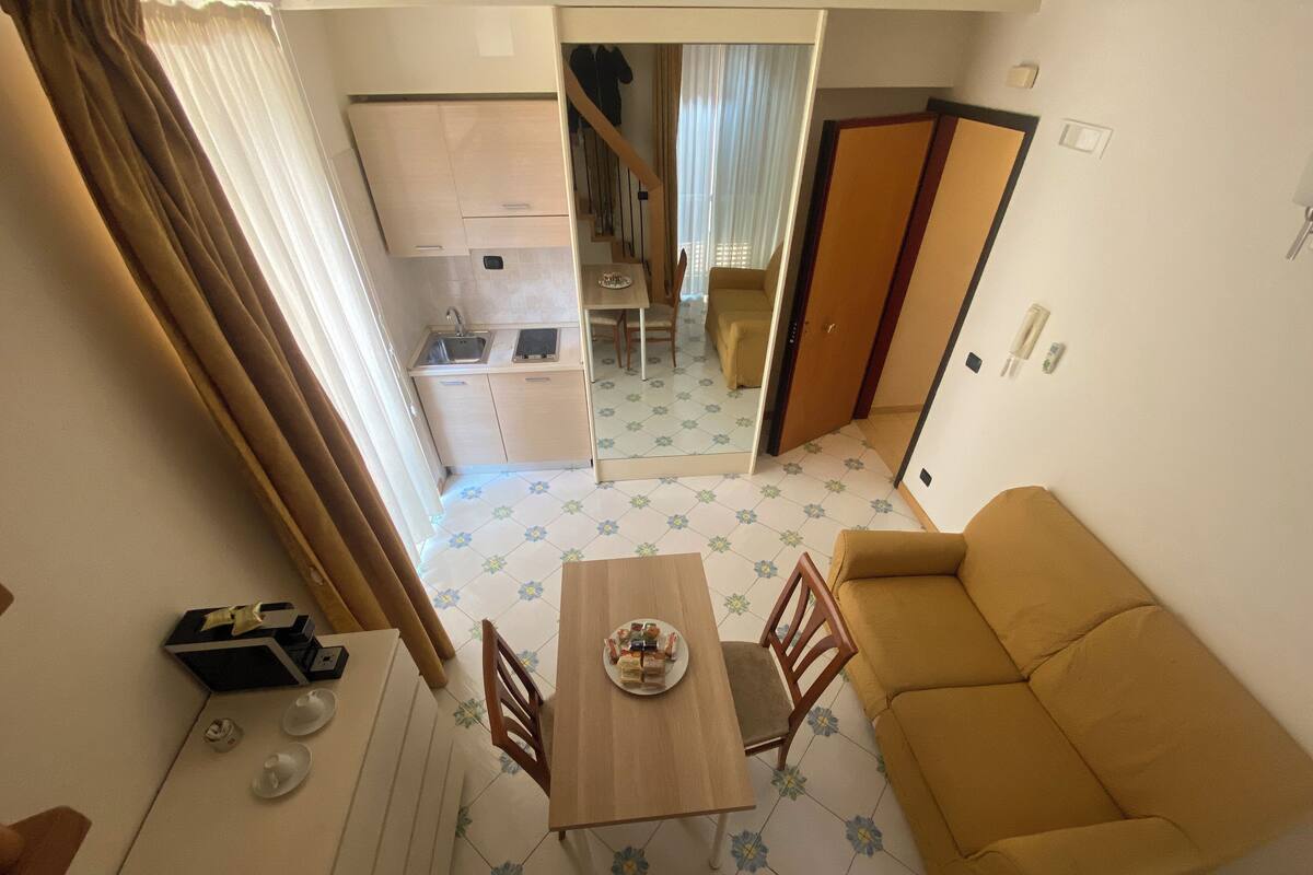 Um espaço compacto com área de refeições, um sofá e uma cozinha ao fundo.