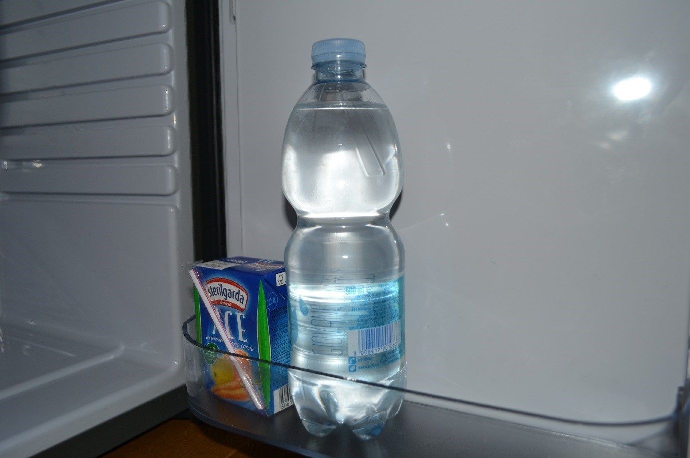 Een koelkast met een waterfles en een melkpak erin.