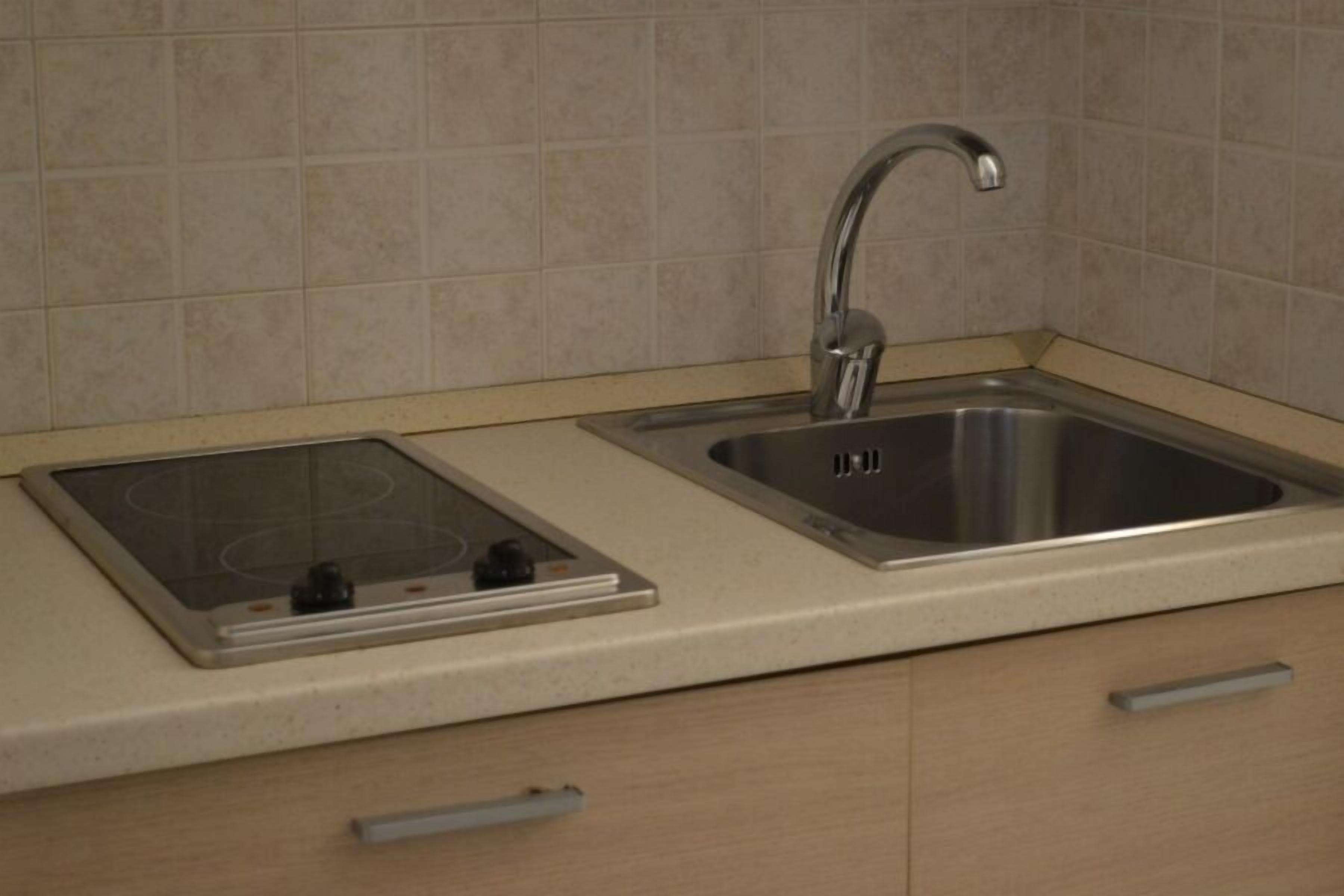 A kitchen with a stainless steel sink, a built-in stovetop, and light-colored cabinetry.