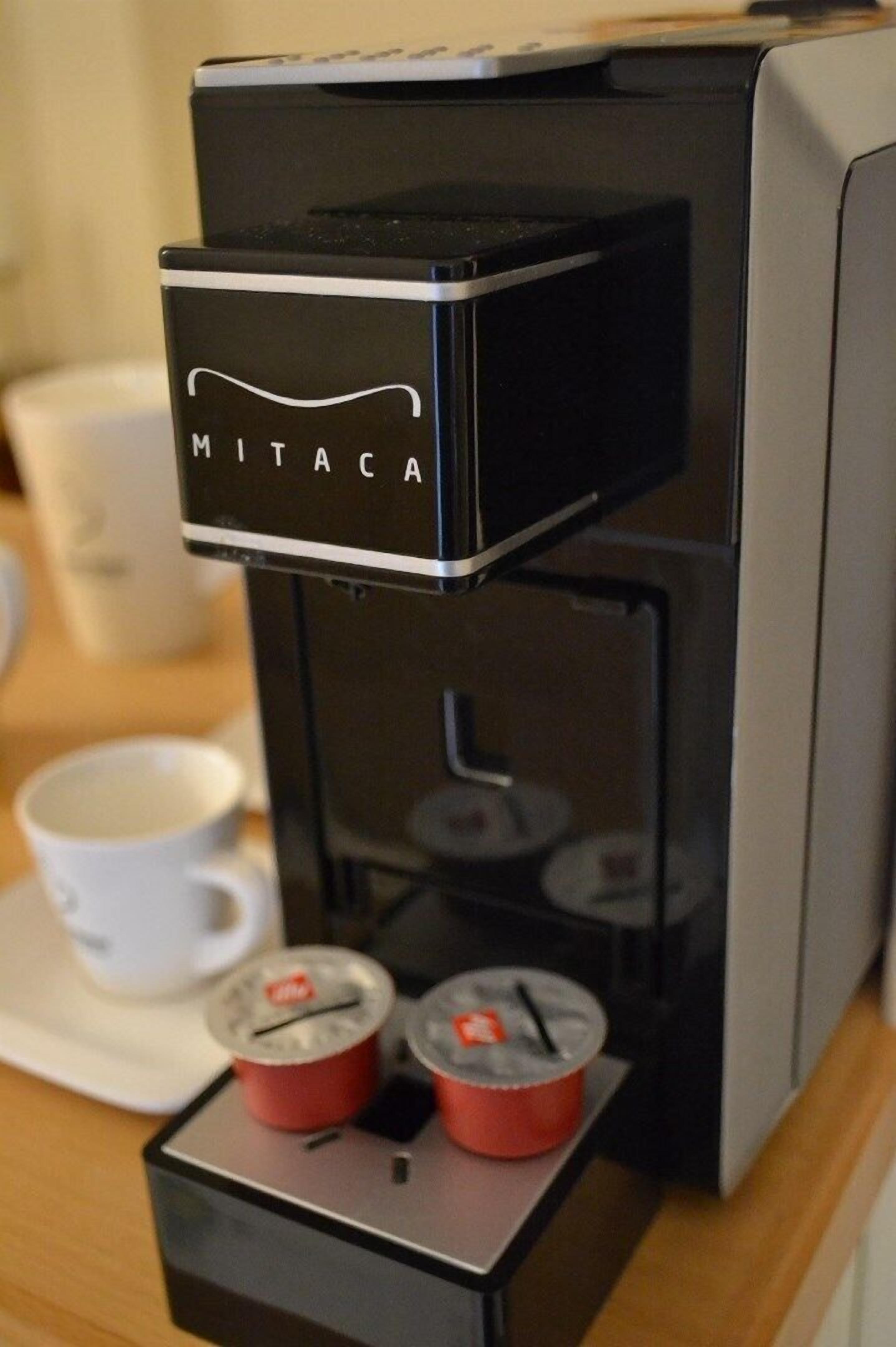 A coffee machine with a brand name visible, a cup of coffee, and a saucer on a table.