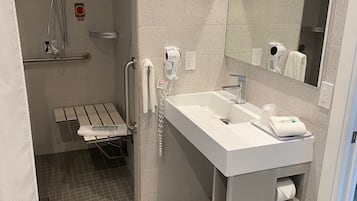 Un baño moderno con ducha, lavabo, espejo y un perchero para toallas.