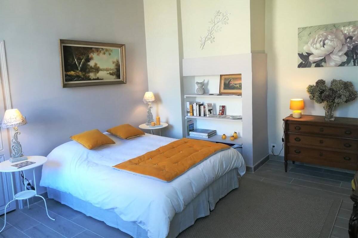 A bedroom with a bed, bedside tables, a dresser, a bookshelf, and a painting on the wall.