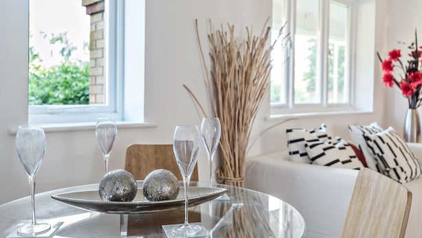 A modern dining area with a glass table, three wine glasses, and decorative silver balls. - 2 Bed Flat, Dedicated Workspace, Parking, 4KTV (London)