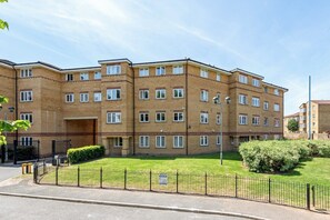 A multi-story residential building with a brick facade, multiple windows, and a well-maintained lawn. - Triple-Train Hub | Step-Free | Parking | Pets (London)