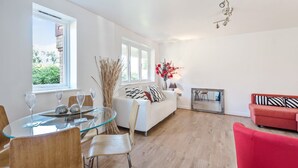 A modern living room with a glass dining table, a red sofa, and a white couch. - 2 Bed Flat, Dedicated Workspace, Parking, 4KTV (London)
