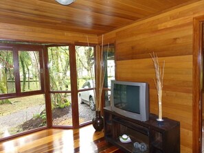 Enjoy a peaceful retreat with a view of lush greenery from the comfort of your room, featuring a large sliding door and a flat-screen TV.