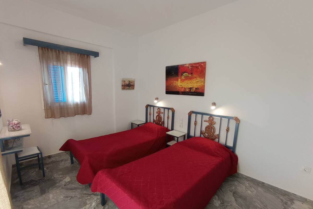 A room with two beds, a small desk, and a window with curtains.