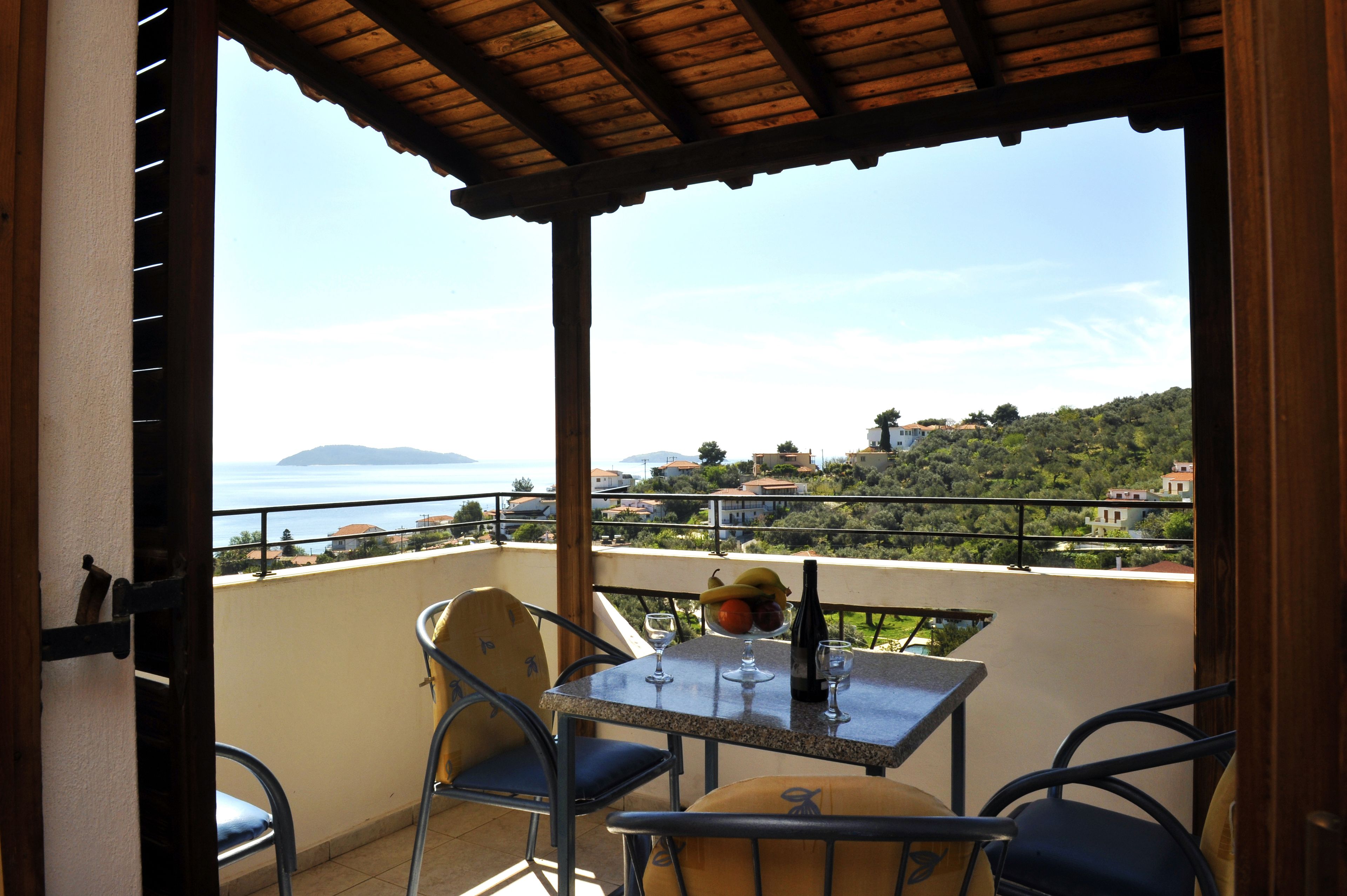 Un balcon avec une table, des chaises et une bouteille de vin.