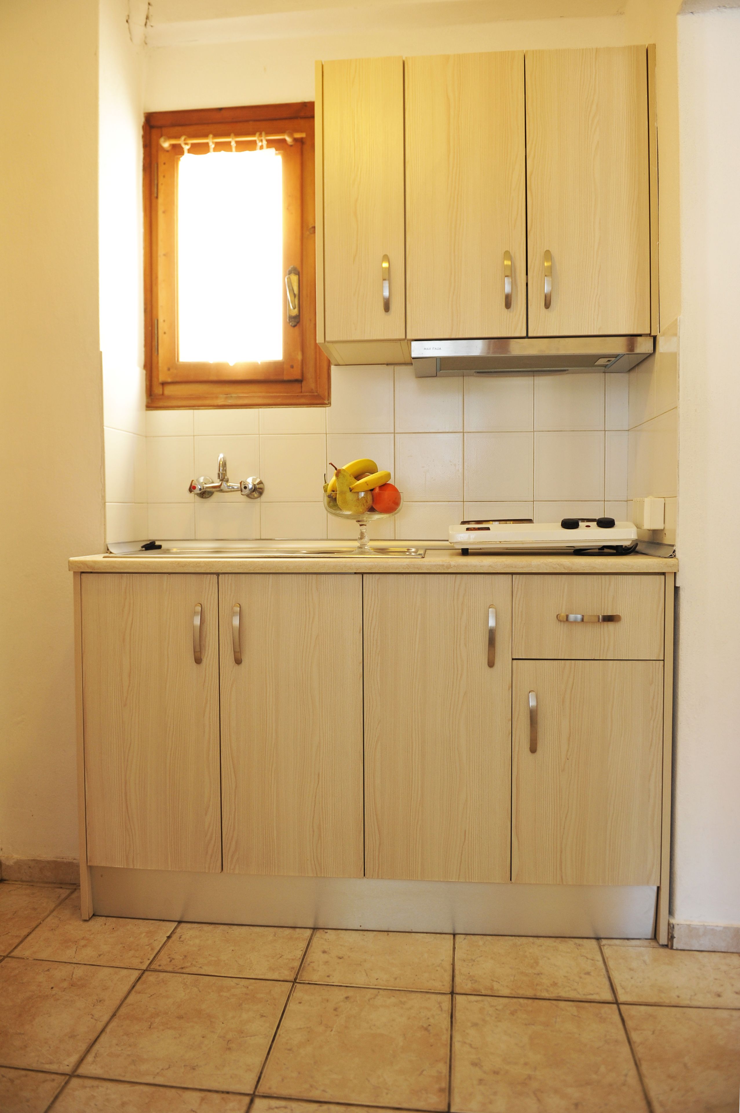 A kitchen with wooden cabinets, a window above the sink, and a tiled floor.