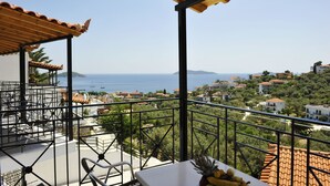 A balcony with a view of the sea, a table with chairs, and a wooden pergola. - Fengeros Village (Skiathos)