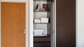A wooden door with a white frame, an open closet with shelves holding folded towels and a box of a hairdryer. - Palermo Golf - Exclusive Apartment (Buenos Aires)