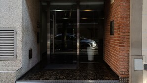 A building entrance with a glass door, a brick wall, and a tiled floor. - Palermo Golf - Exclusive Apartment (Buenos Aires)