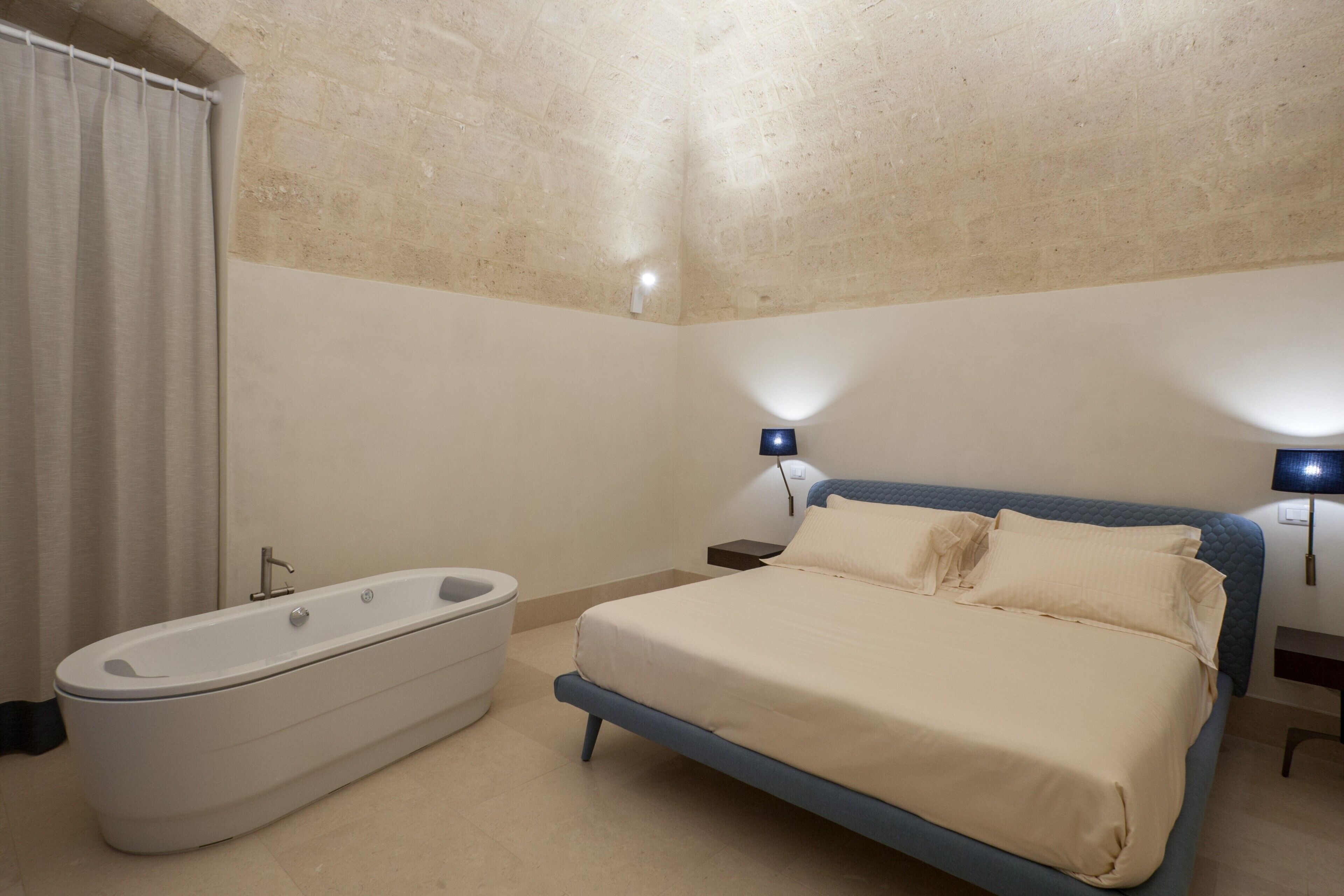 Una camera da letto con un letto grande, una vasca da bagno e due lampade ai lati del letto.