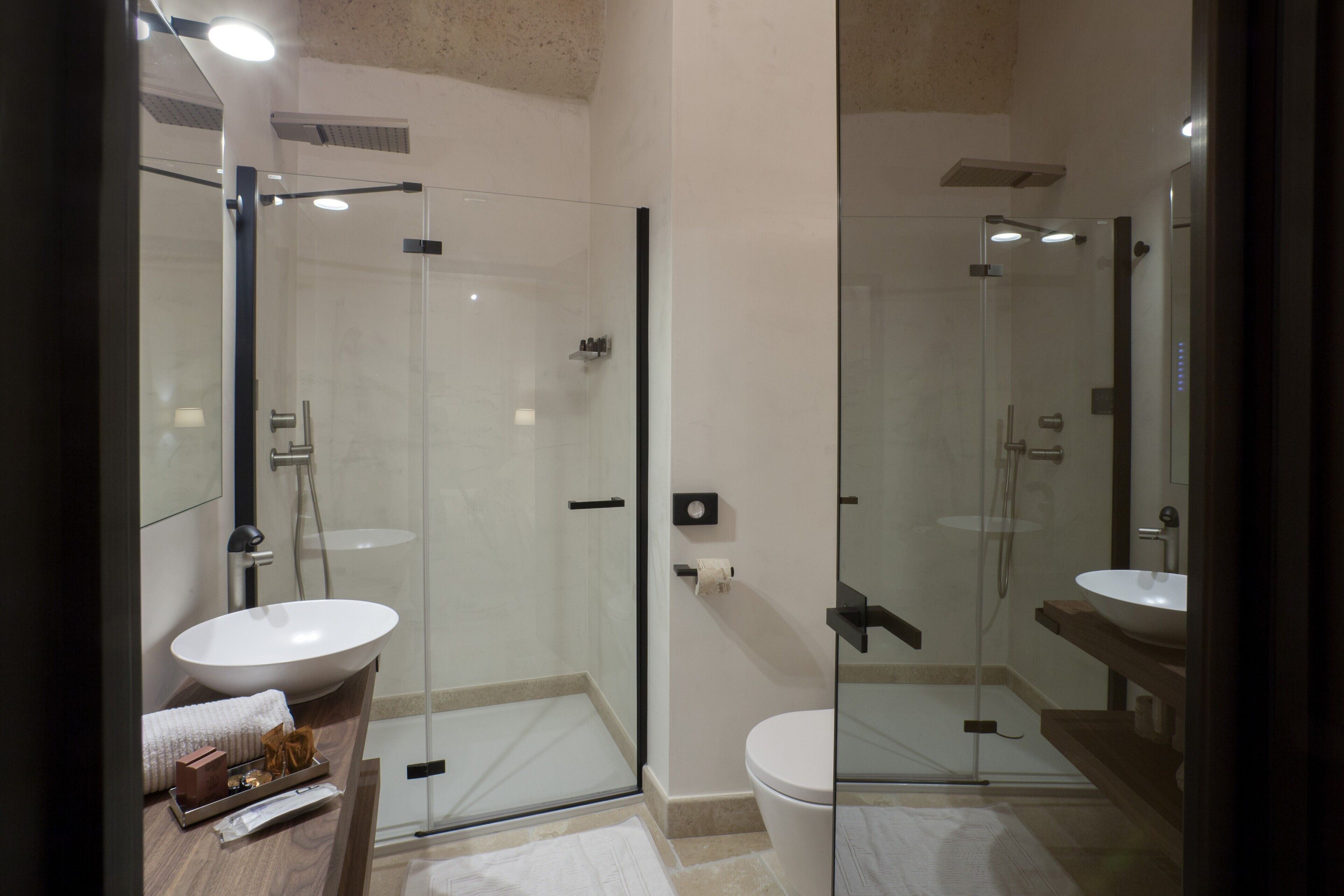 Une salle de bain moderne avec une douche à parois de verre, un lavabo blanc et un grand miroir.