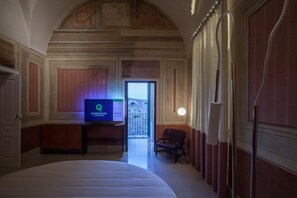 A hotel room with a bed, a television displaying a screen, a chair, and a view through a door.