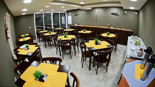 A dining area with multiple tables and chairs, a counter with a menu, and a fire extinguisher on the wall. - Wanna Hotel (Lins)