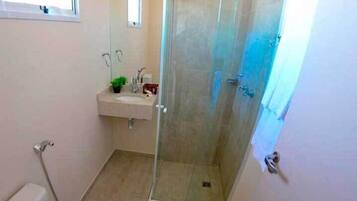A bathroom with a glass-enclosed shower, a sink with a mirror, and a toilet.
