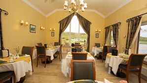 A dining area with multiple tables, chairs, and a chandelier. - The 19th Lodge Ballybunion (Ballybunion)