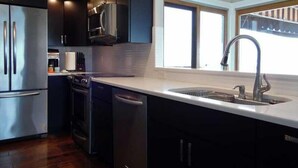 A modern kitchen with stainless steel appliances, a dishwasher, and a large window providing natural light.
