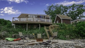 A two-story house with a balcony, a wooden deck, and a small boat.