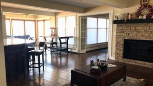 A spacious living room with hardwood flooring, a fireplace, and a dining area with a large window.
