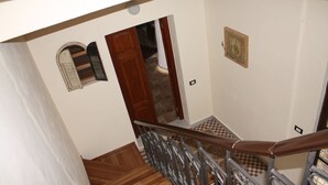 A staircase with a wooden handrail and a checkered floor pattern. - Batarà B&B (Agrigento)