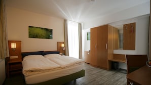 A hotel room with a bed, a desk, a chair, and a wardrobe. - Hotel Drei Kaiserberge (Goeppingen)
