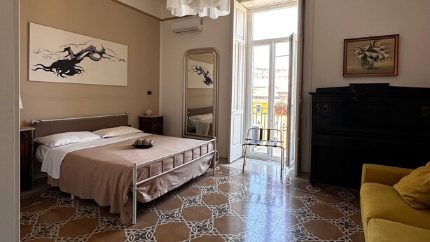 Une chambre à coucher avec un lit, un miroir, une commode et un fauteuil jaune.