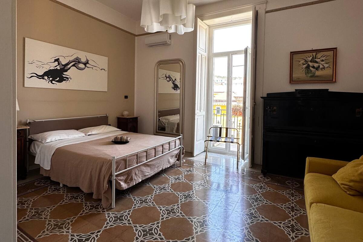 A bedroom with a bed, a mirror, a dresser, and a yellow armchair.