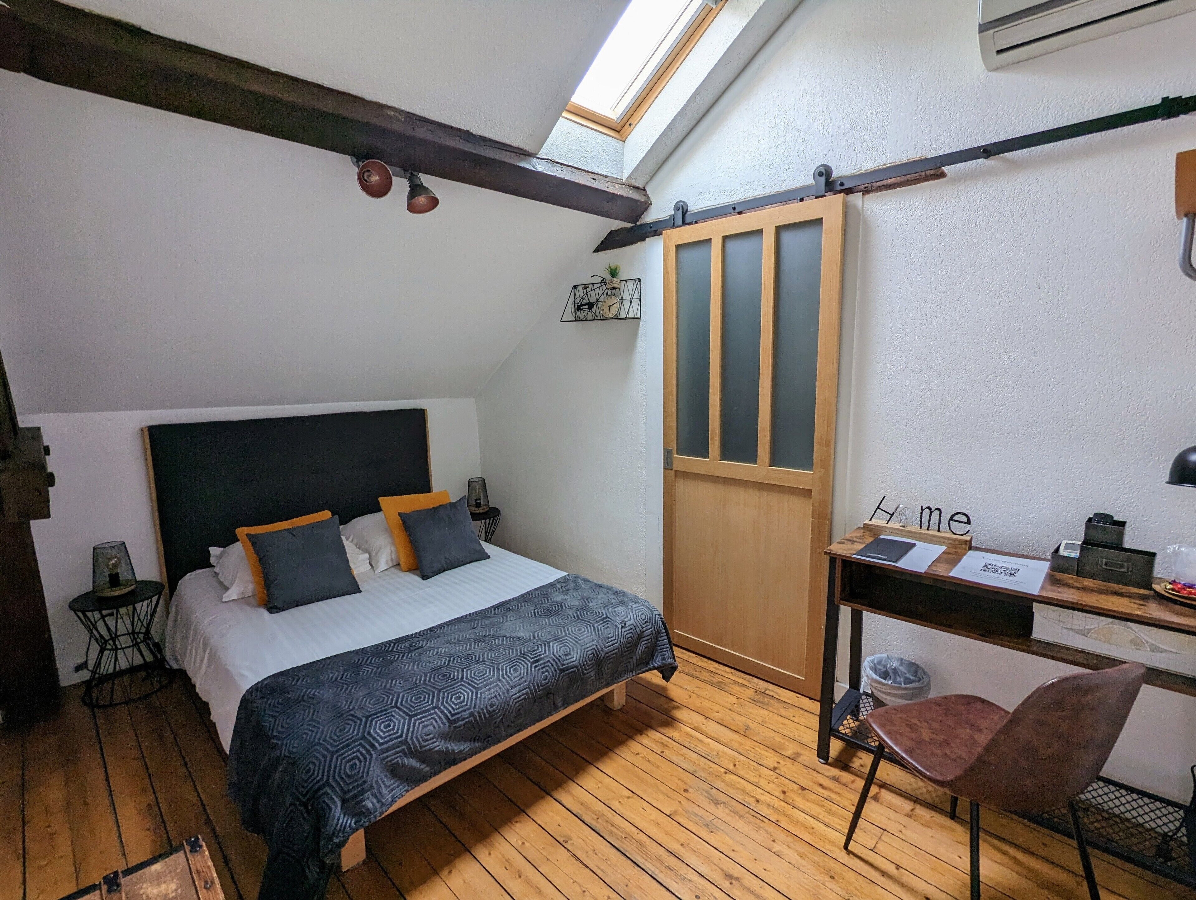 Un dormitorio con cama, escritorio, silla, tragaluz y armario.