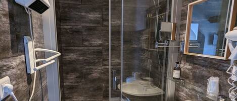 A modern bathroom with a glass-enclosed shower, a white sink, and a mirror.