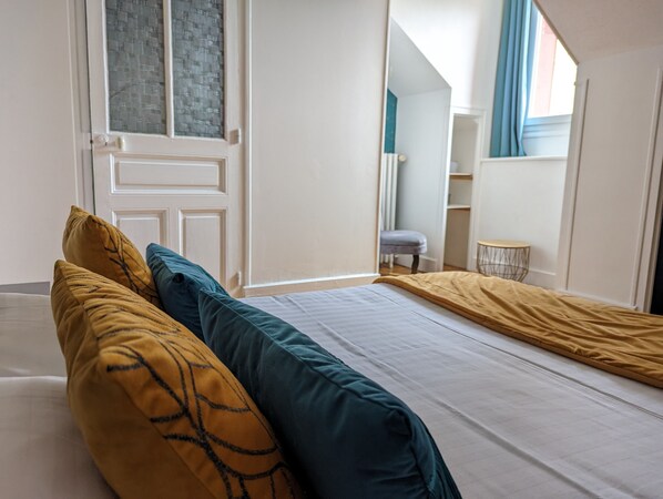 A bedroom with a bed, pillows, a window, and a door.