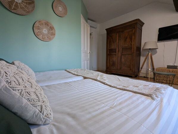 A bedroom with a large bed, a wooden wardrobe, and a floor lamp. - Hotel La Tourelle du Beffroi (Bourbon-Lancy)