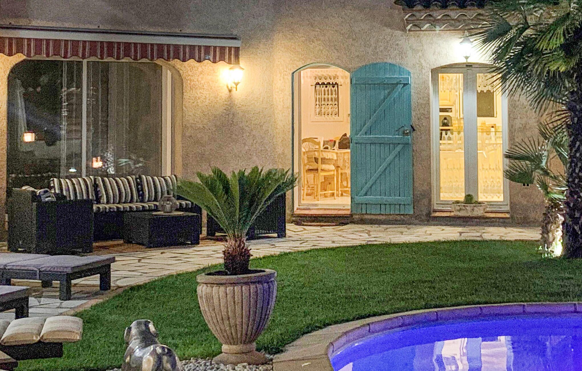 Une cour avec une piscine, un canapé, une table à manger et une porte avec une fenêtre.