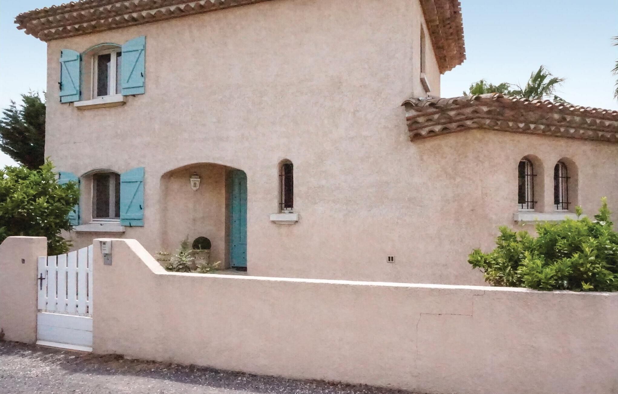 A two-story building with a beige stucco exterior, blue shutters, and a tiled roof.