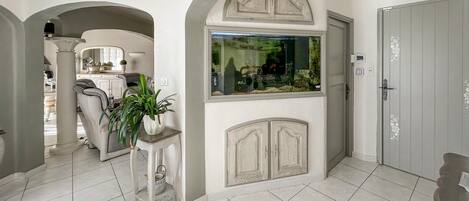 A spacious hallway with a tiled floor, a large aquarium, and a door with a decorative handle.