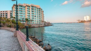 A waterfront hotel with a brick walkway, a lamp post, and a view of the sea. - Island Studio | Stunning Waterfront Getaway (Condado Lagoon Villas)