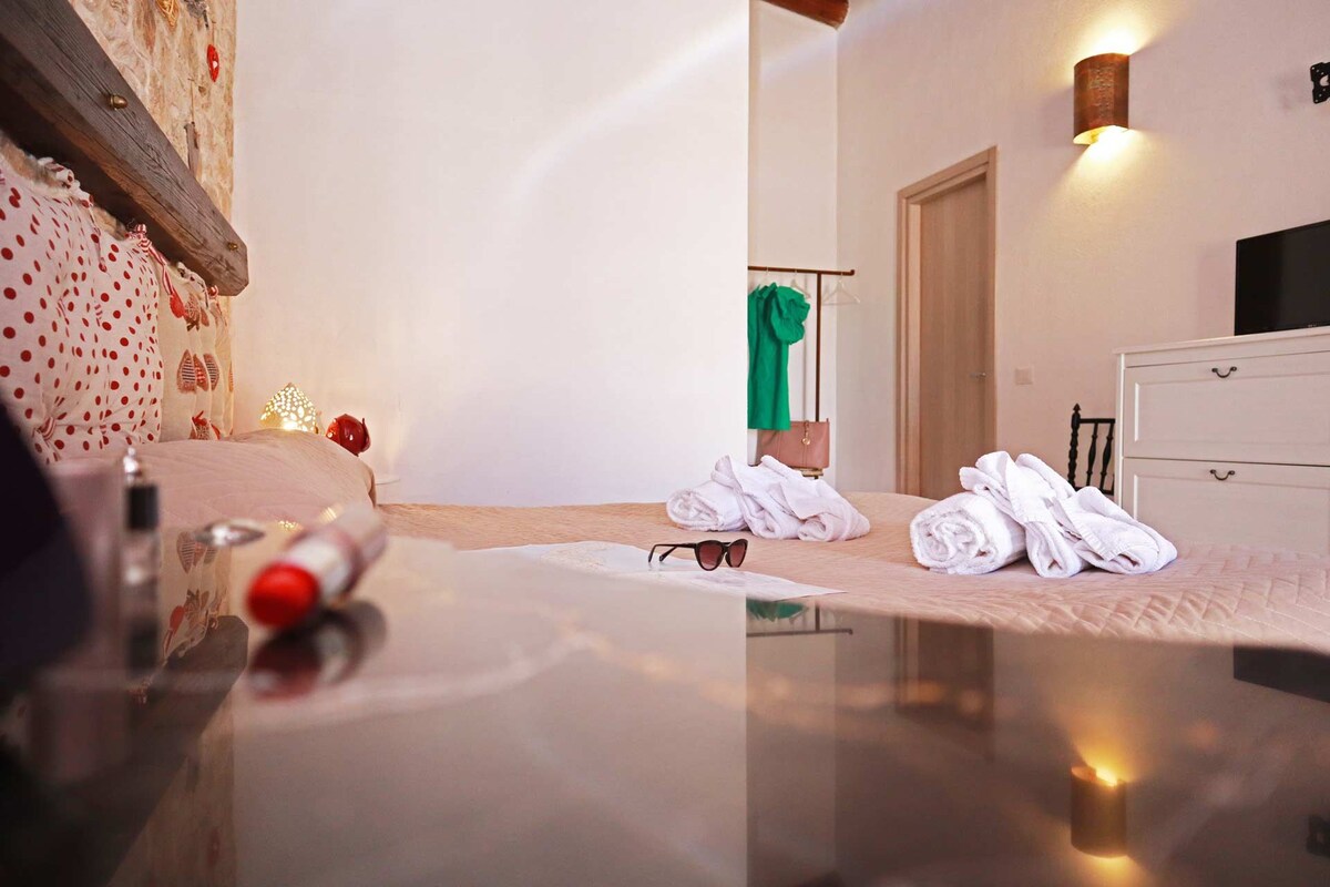 A neatly arranged hotel room with a bed, a dresser, and a mirror.