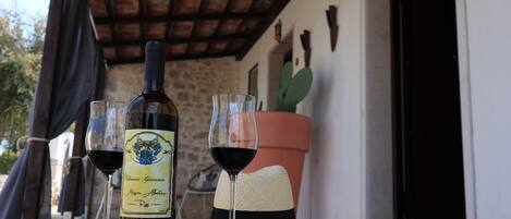 Una mesa con una botella de vino, dos copas de vino tinto y un sombrero de paja.