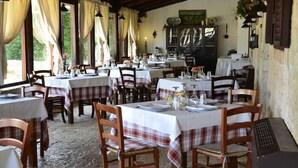 Um restaurante com várias mesas preparadas para refeições, cadeiras de madeira e decoração rústica.