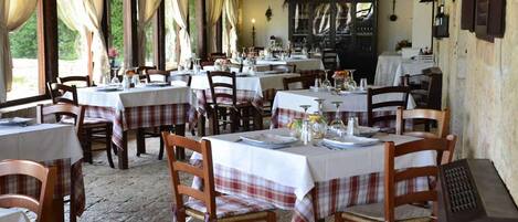 A restaurant with multiple tables set for dining, wooden chairs, and a rustic interior.