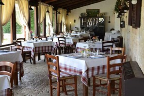 A restaurant with multiple tables set for dining, wooden chairs, and a rustic interior. - Masseria Alberotanza (Conversano)