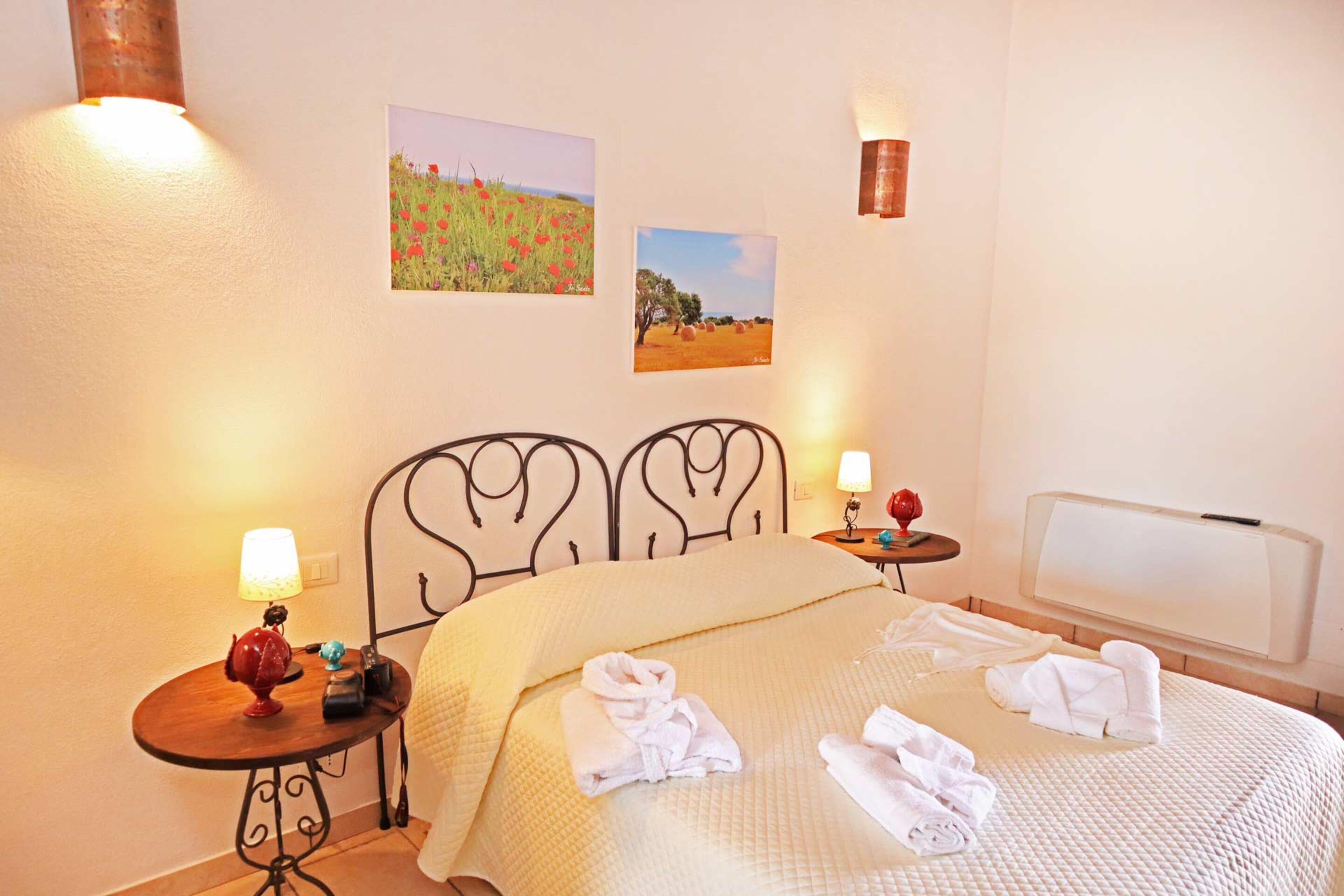 Una camera d'albergo con un letto, due comodini, una lampada e due lampade a parete.