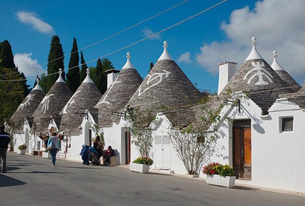 Una hilera de edificios tradicionales con techos cónicos y paredes blancas bajo un cielo despejado.