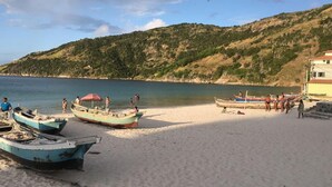 Una playa con barcos, una orilla arenosa y un paisaje montañoso.