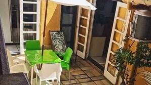 Un pequeño espacio al aire libre con piscina, una mesa con sillas y un paraguas blanco.
